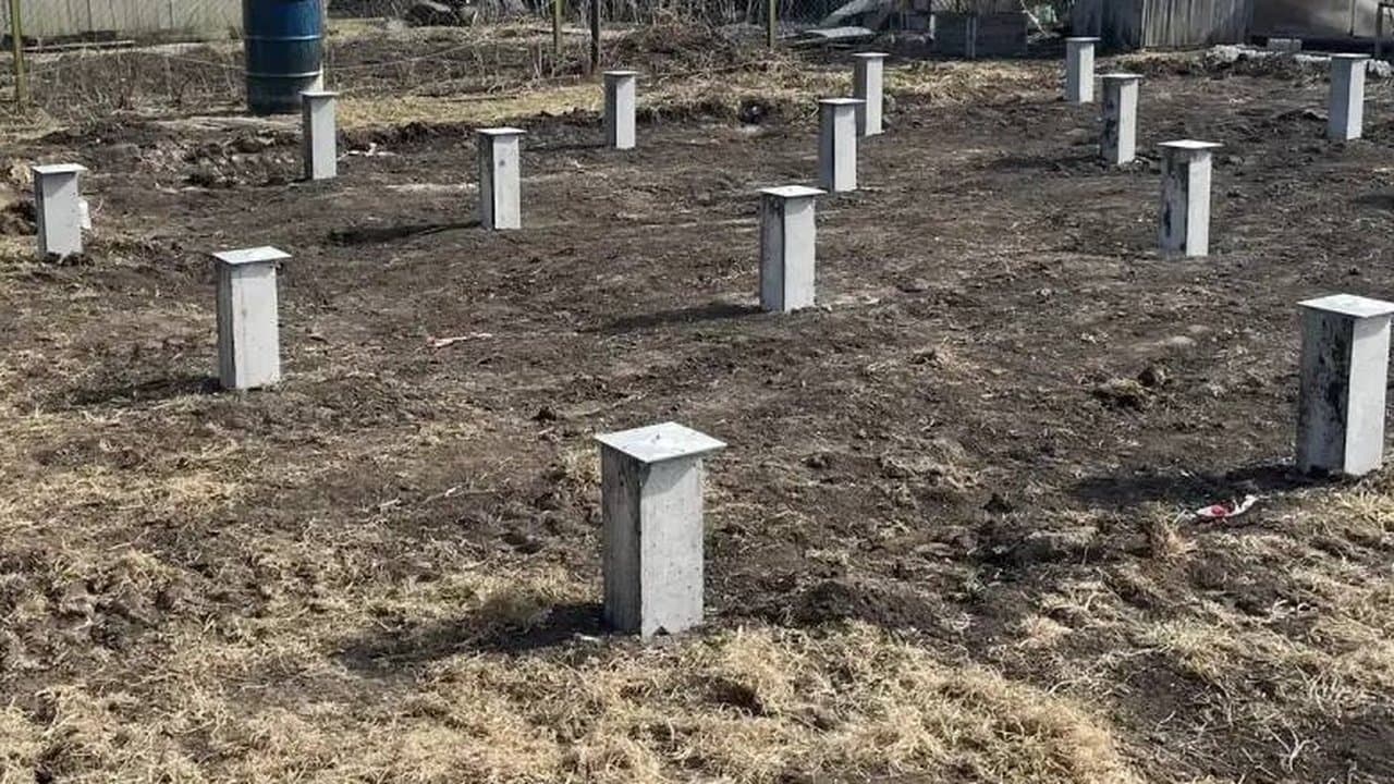 Бетонные сваи будущего дома на участке весной: земля перекопана, стен ещё нет